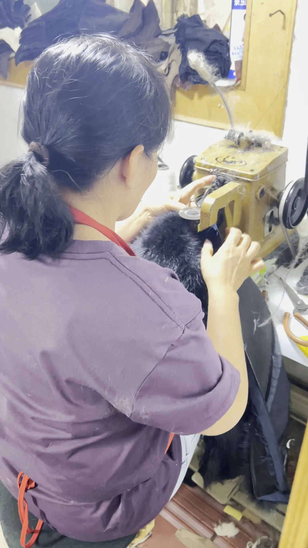 Worker seen from behind at a garment sewing workstation in a real workshop video